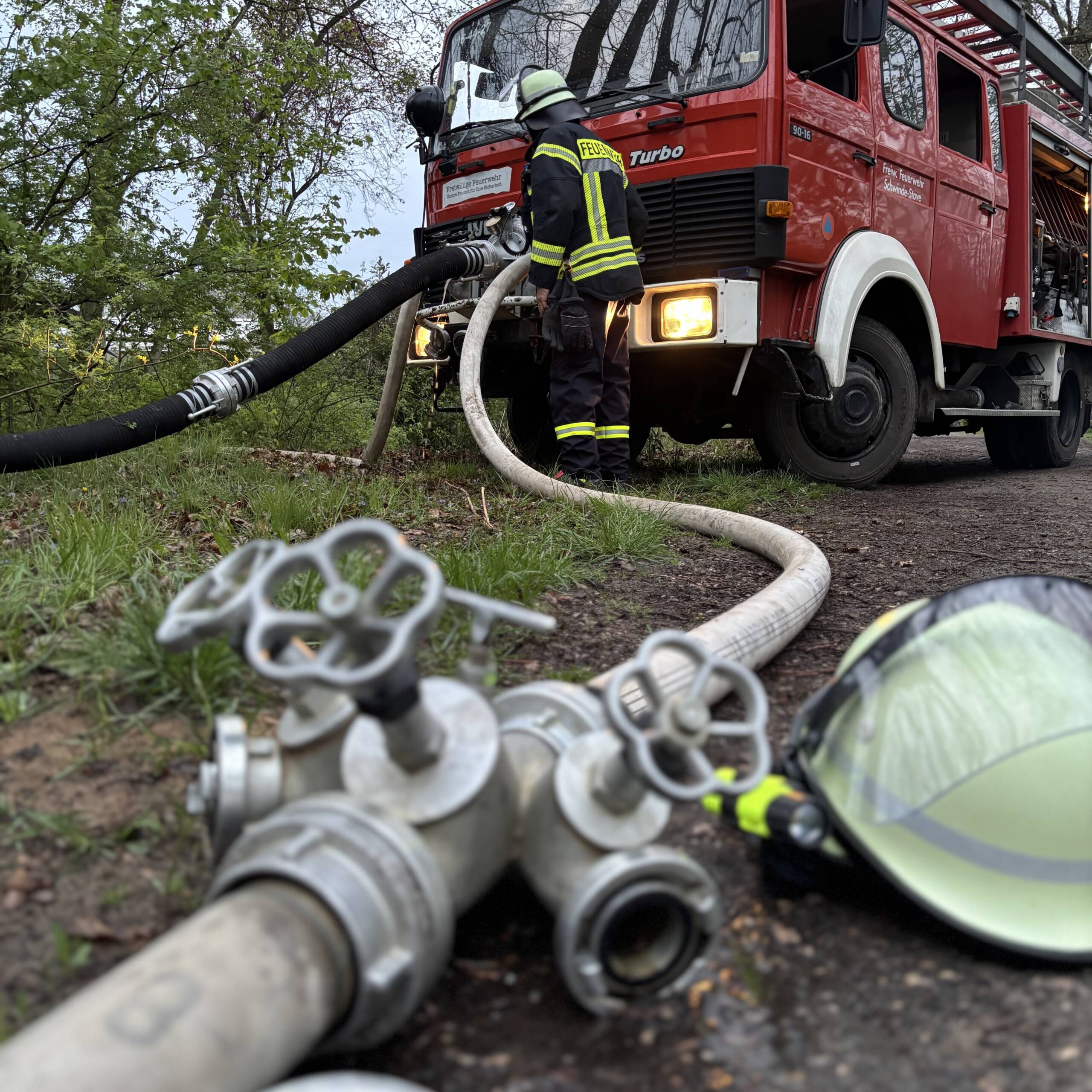 Verteiler und Helm vor einem Löschfahrzeug