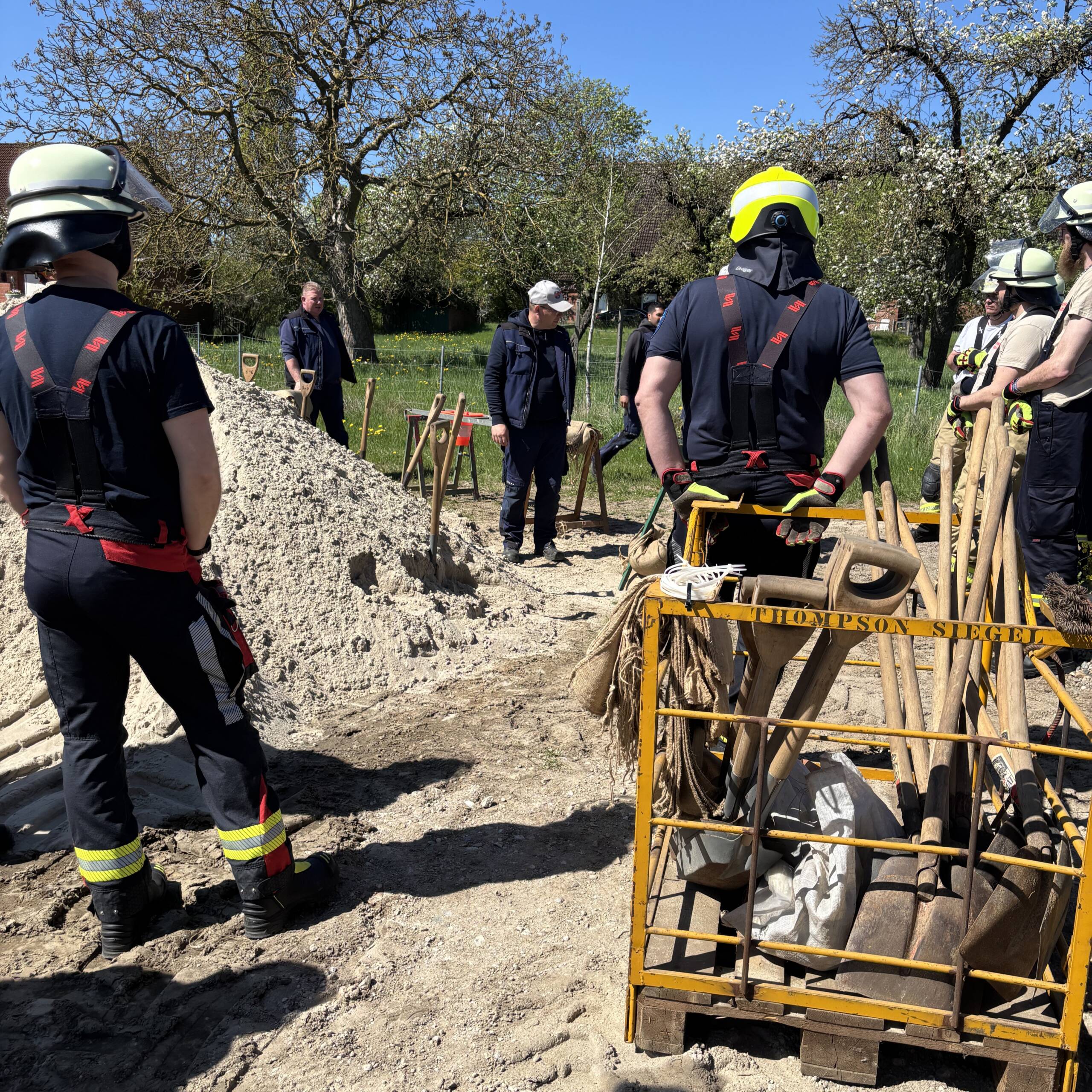 Viele Feuerwehrleute vor einem Sandberg