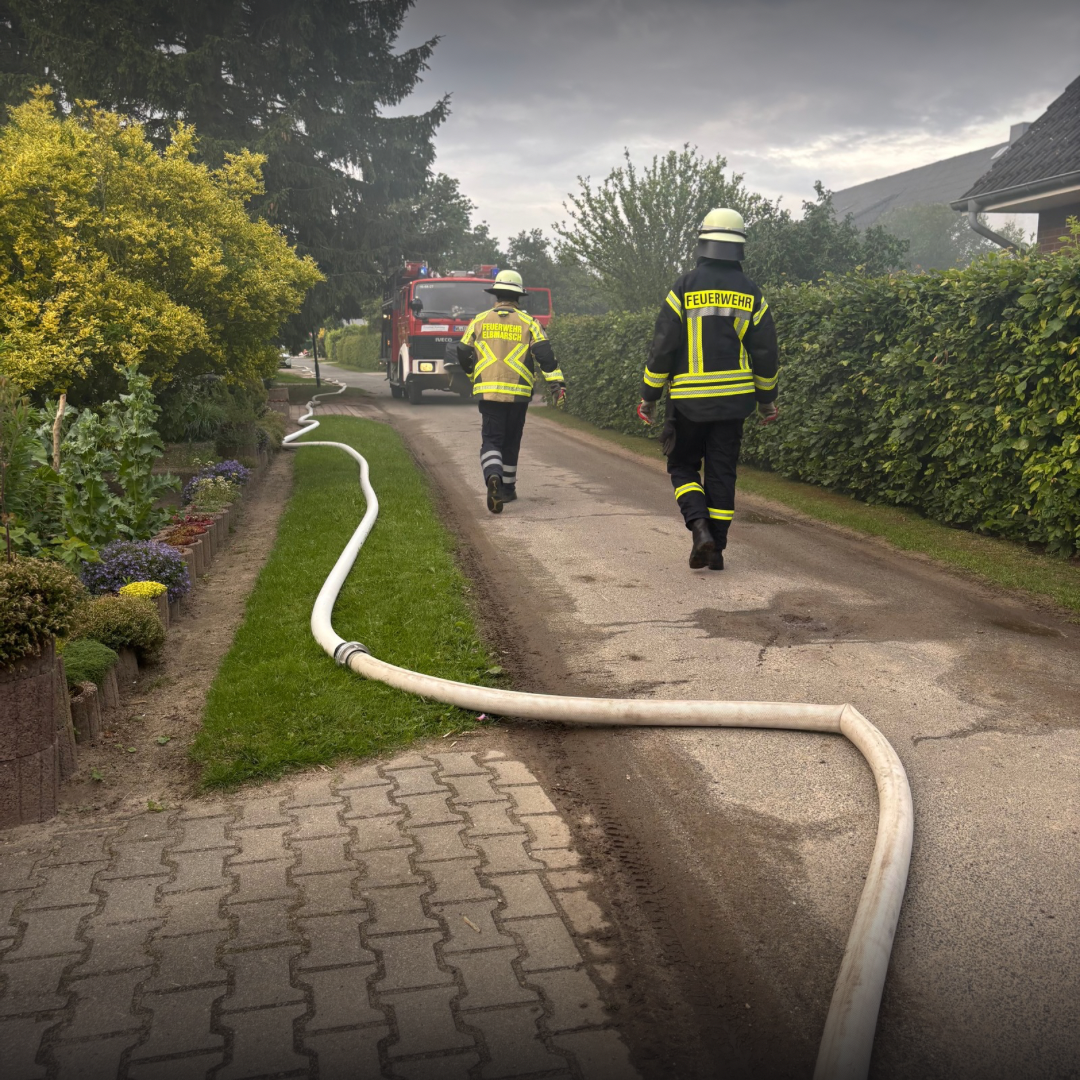 Zwei Feuerwehrleute laufen zu einem Löschfahrzeug