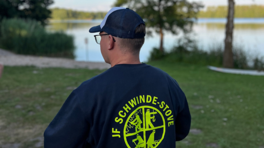 Eine Person im Pullover vor einem See