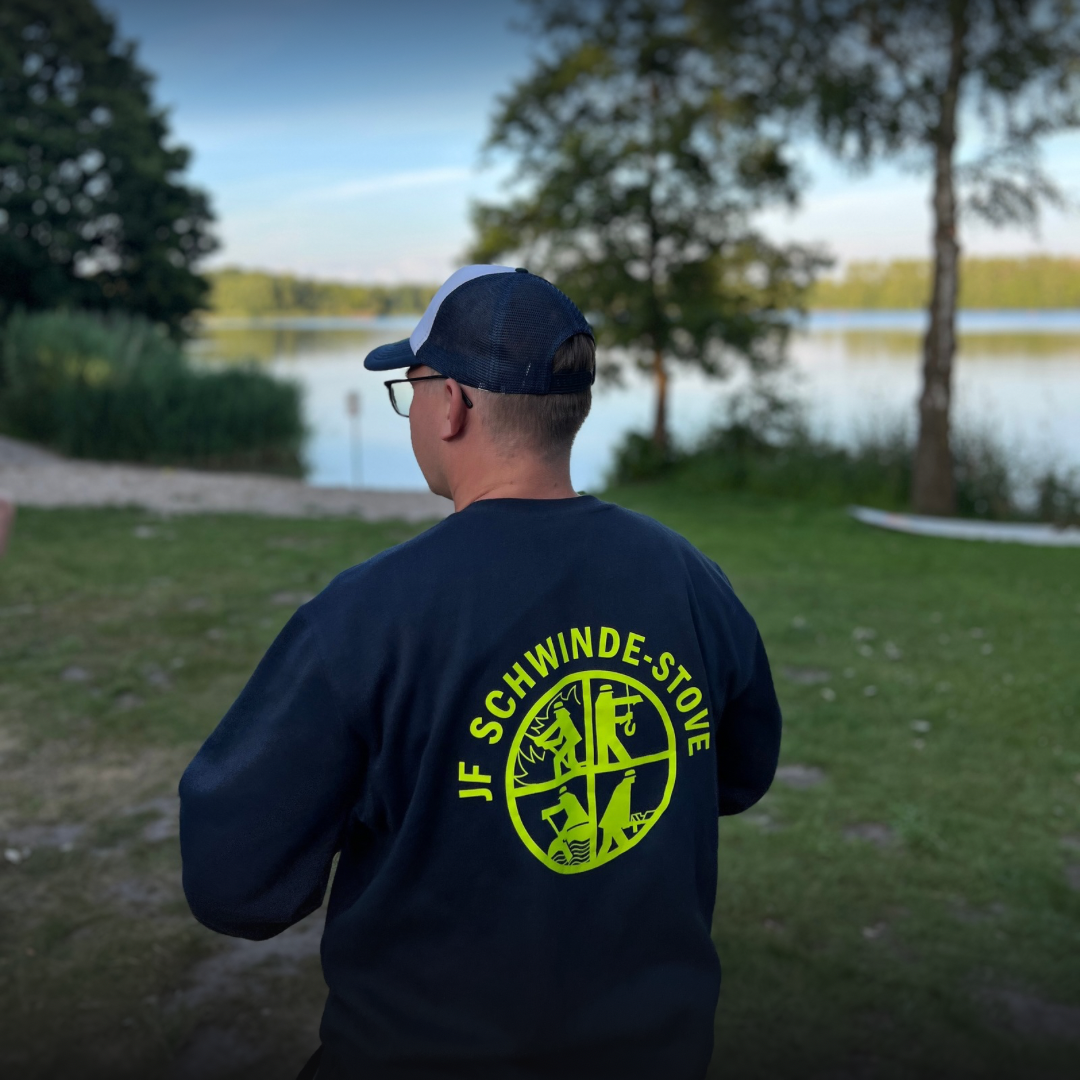 Eine Person im Pullover vor einem See