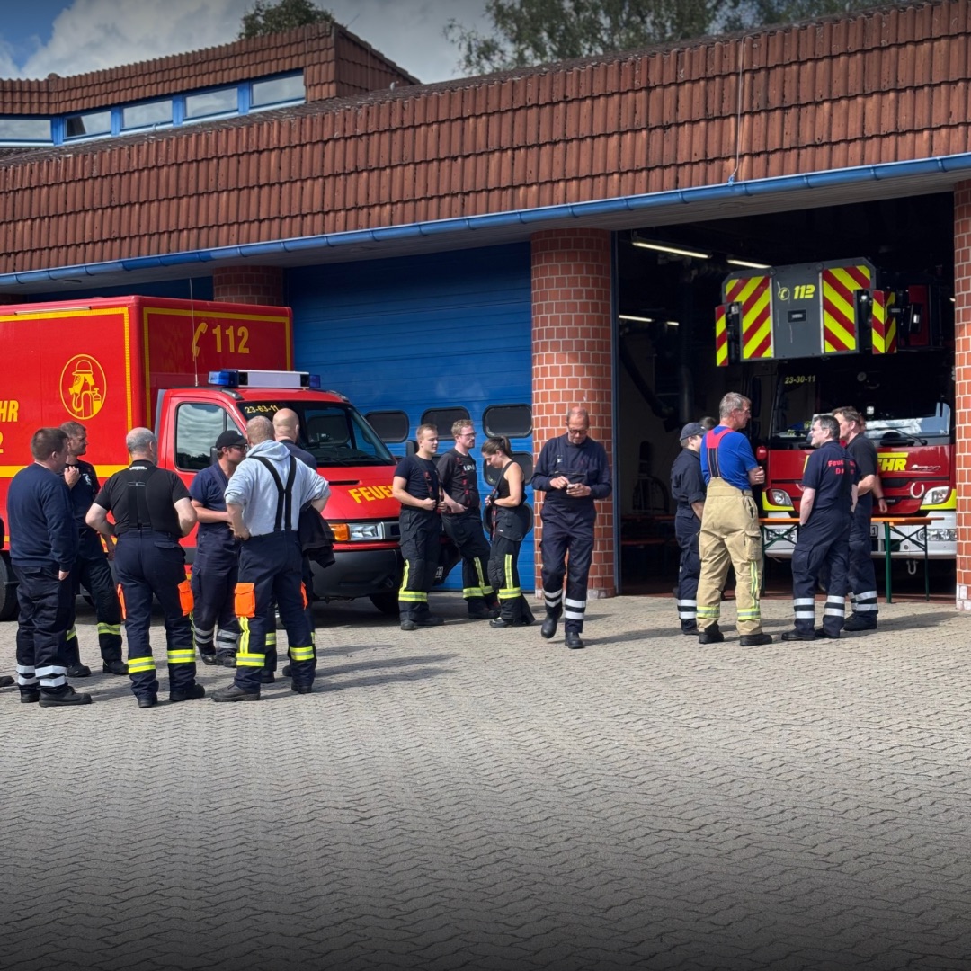 Feuerwehrleute stehen vor einer Feuerwache