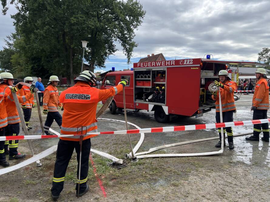 Feuerwehrleute und ein Feuerwehrfahrzeug hinter einer Absperrung