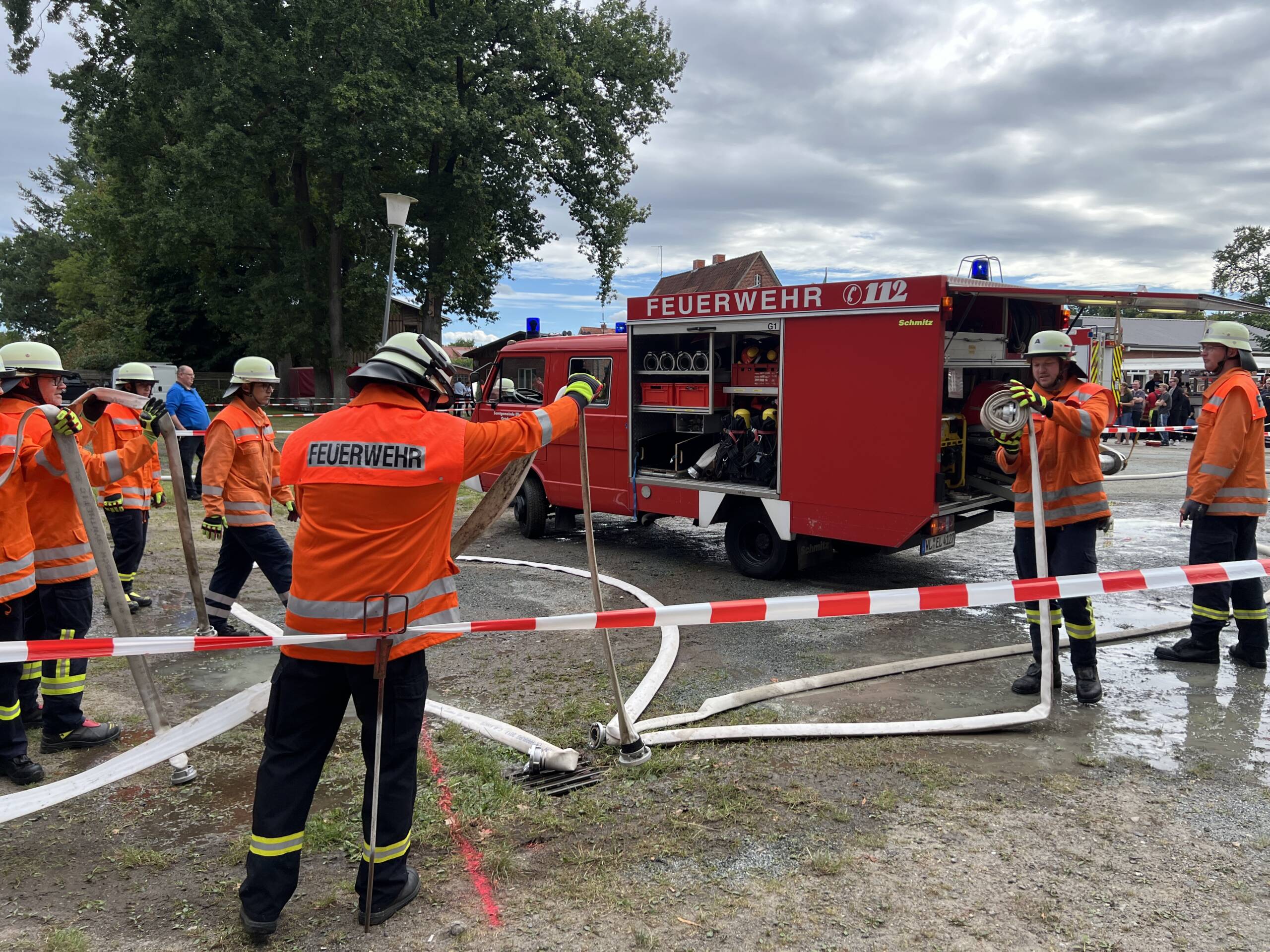 Feuerwehrleute und ein Feuerwehrfahrzeug hinter einer Absperrung
