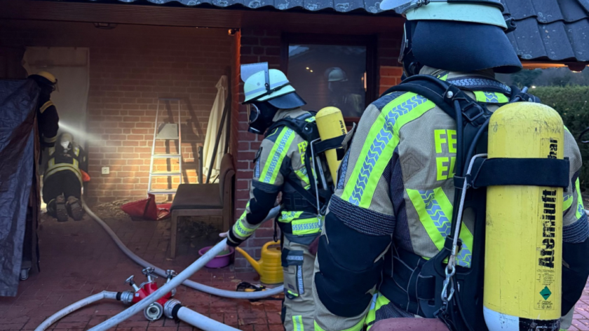 Atemschutzgeräteträger vor einem verqualmten Haus