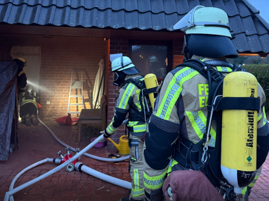 Atemschutzgeräteträger vor einem verqualmten Haus