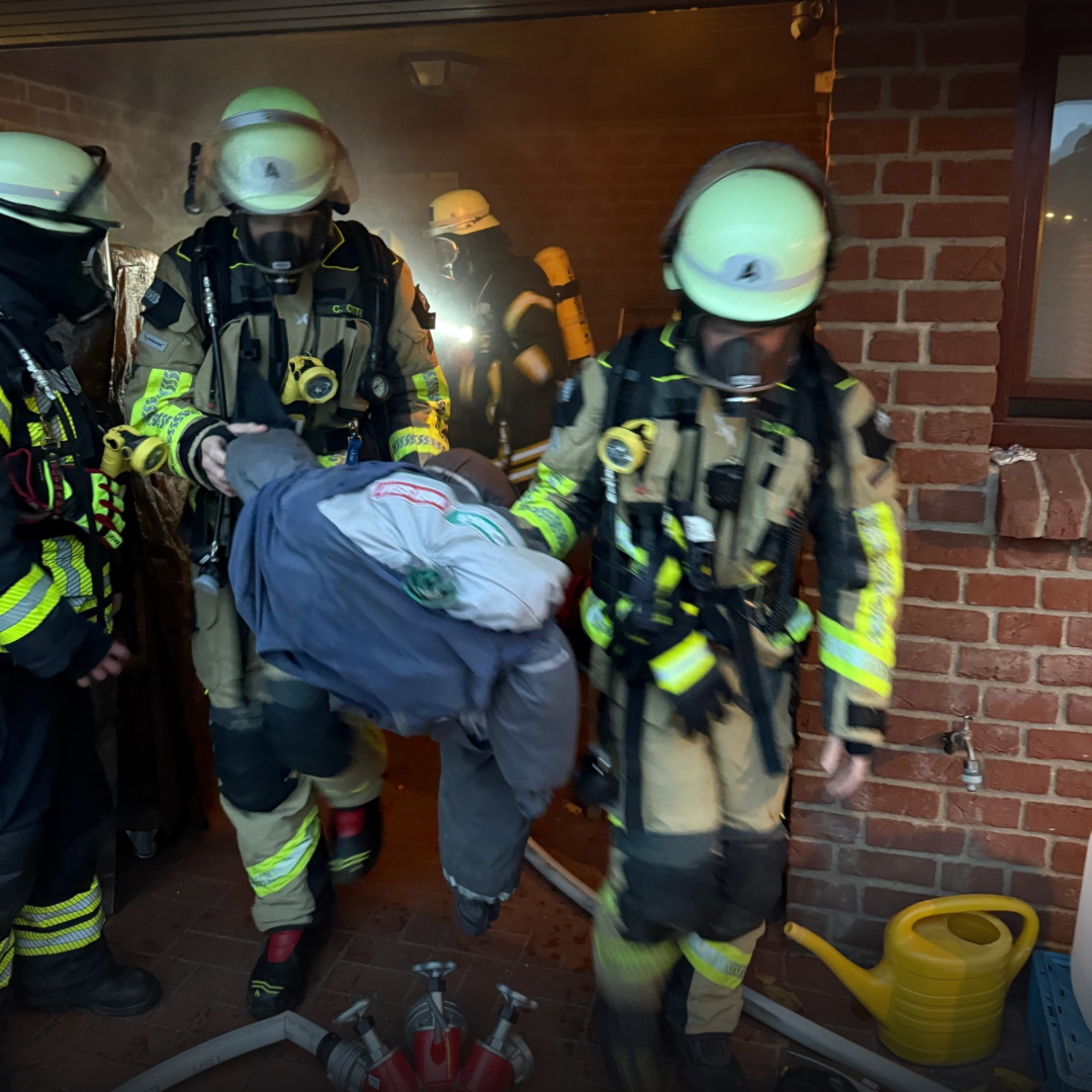 Atemschutzträger bringen eine Puppe aus dem Haus
