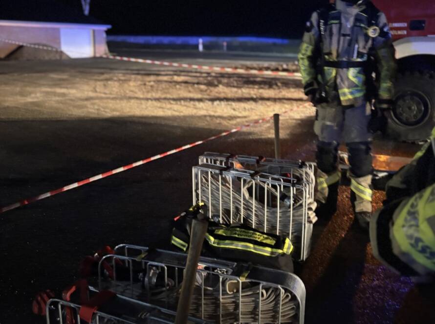 Schlauchkörbe und Einsatzkräfte in Bereitstellung hinter einer Absperrung