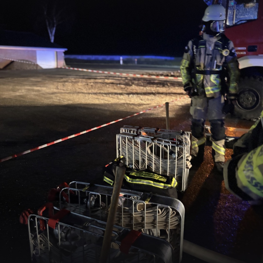 Schlauchkörbe und Einsatzkräfte in Bereitstellung hinter einer Absperrung