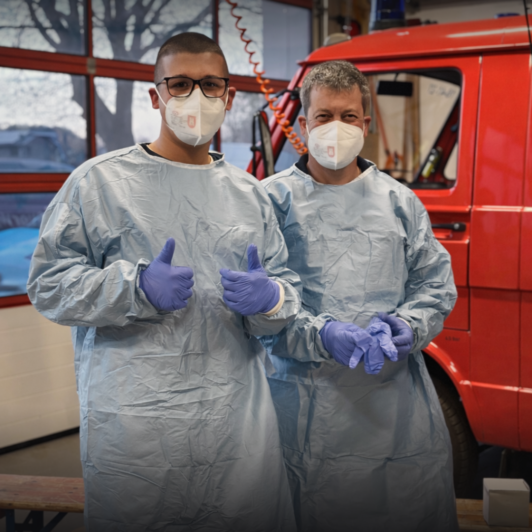 Zwei Männer mit Schutzausrüstung vor einem Feuerwehrfahrzeug