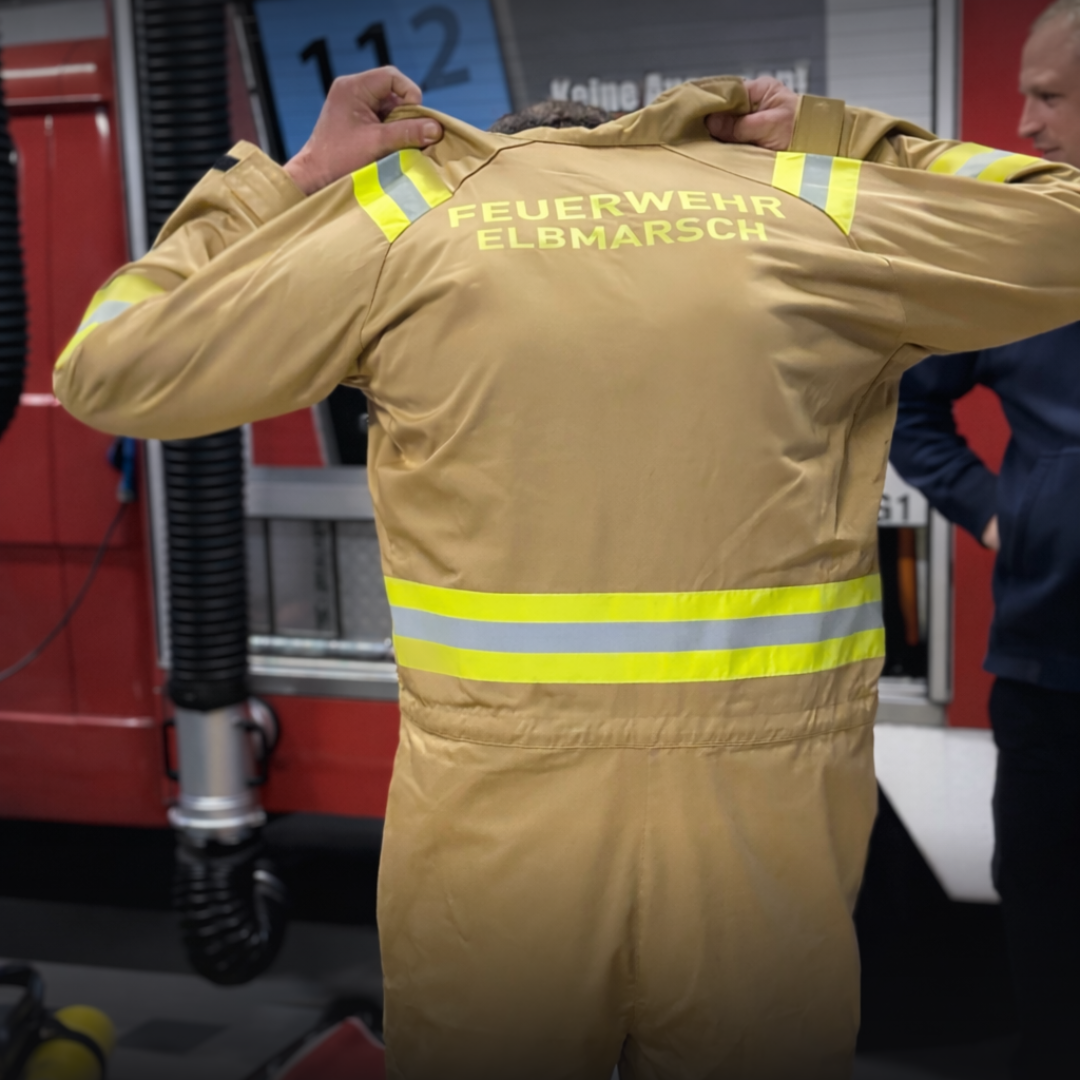 Ein Mann zieht einen Trainingsanzug der Feuerwehr Elbmarsch an