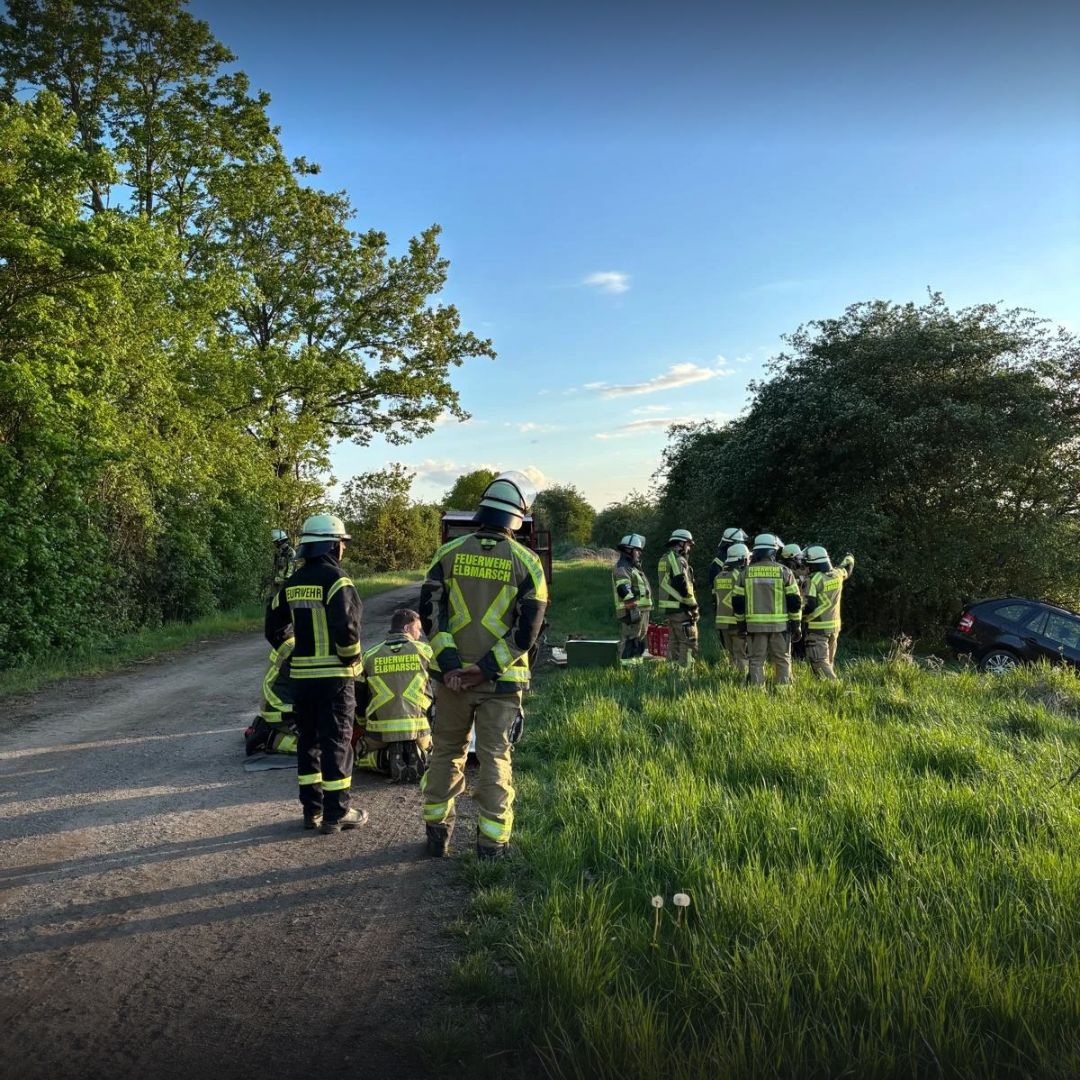 Feuerwehrleute um einen PKW im Graben