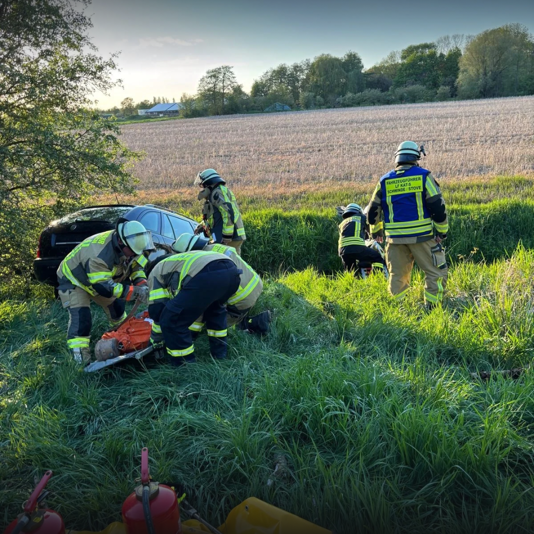 Feuerwehrleute um einen PKW im Graben
