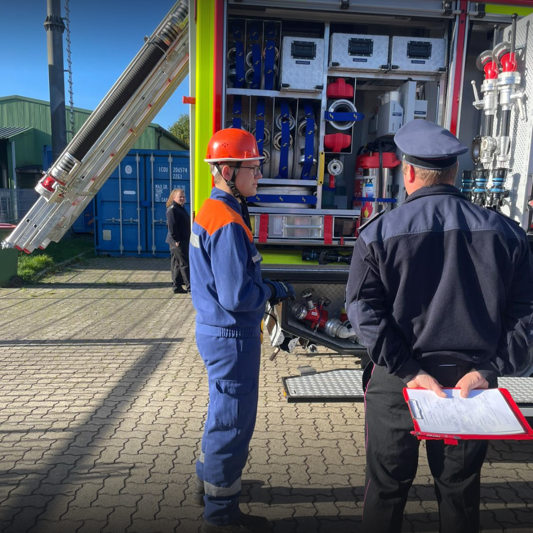 Jugendfeuerwehrmitglied vor einem Löschfahrzeug