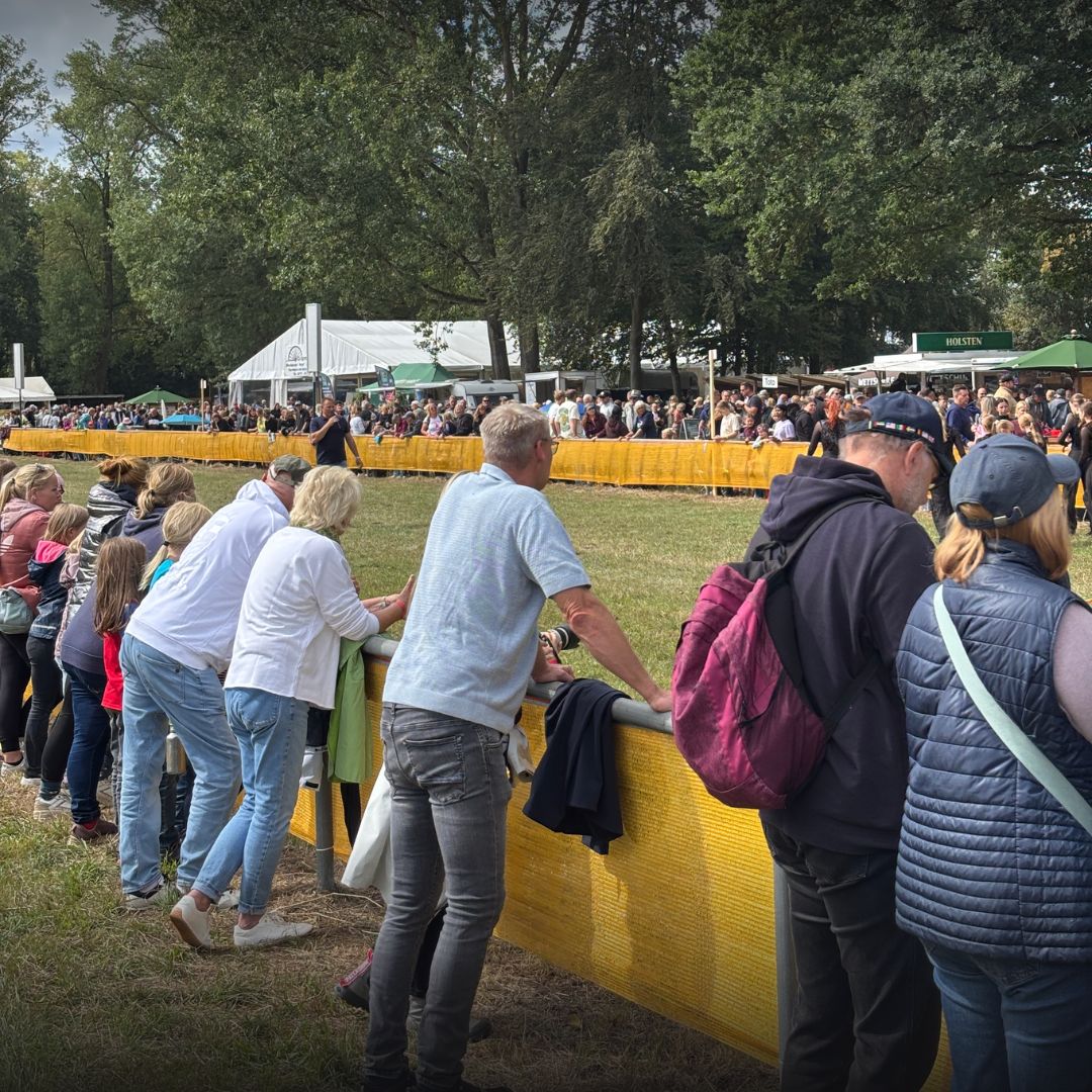 Besucher stehen bei einer Veranstaltung hinter einer Absperrung
