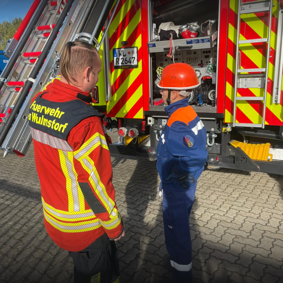 Jugendfeuerwehrmitglied vor einem Löschfahrzeug