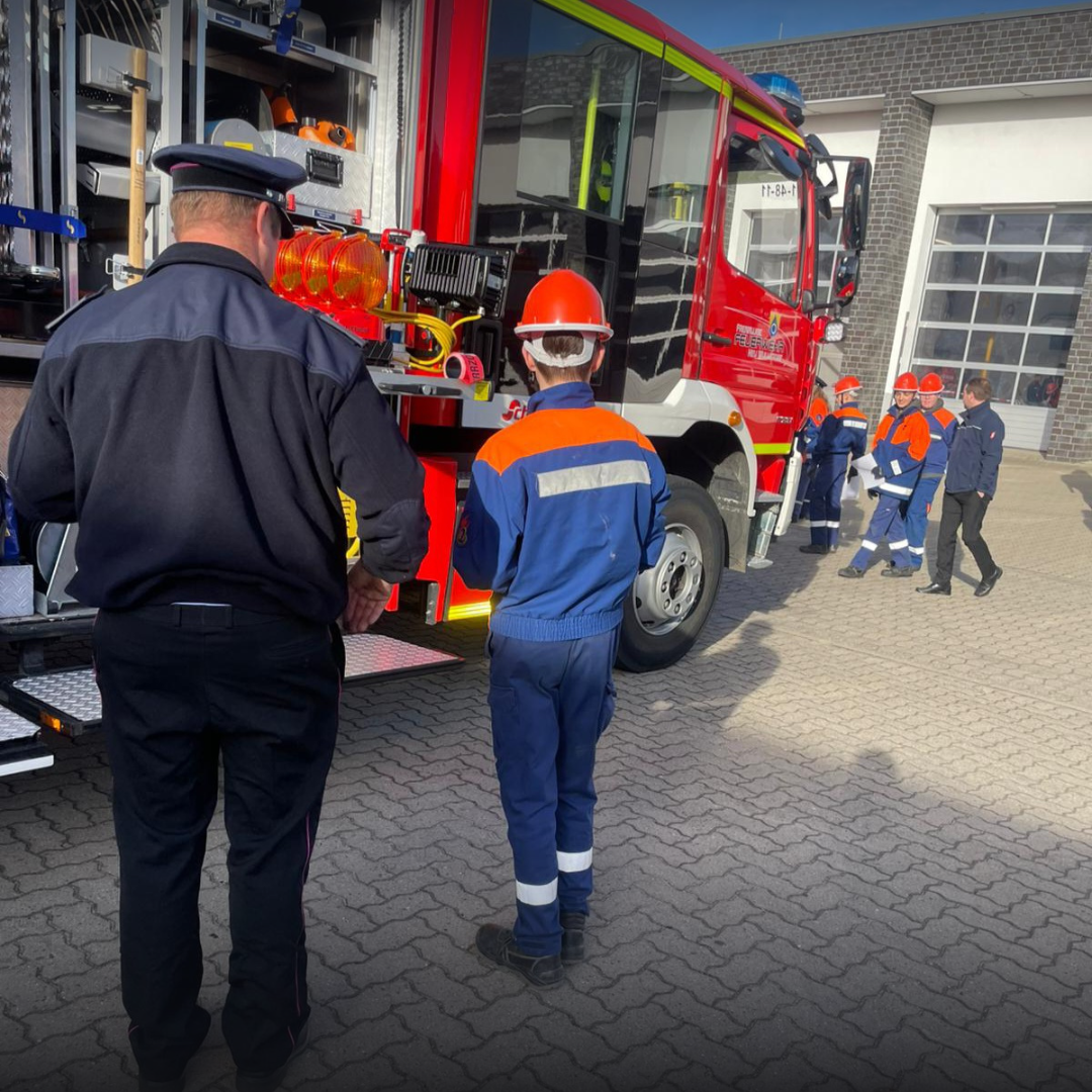 Jugendfeuerwehrmitglied vor einem Löschfahrzeug