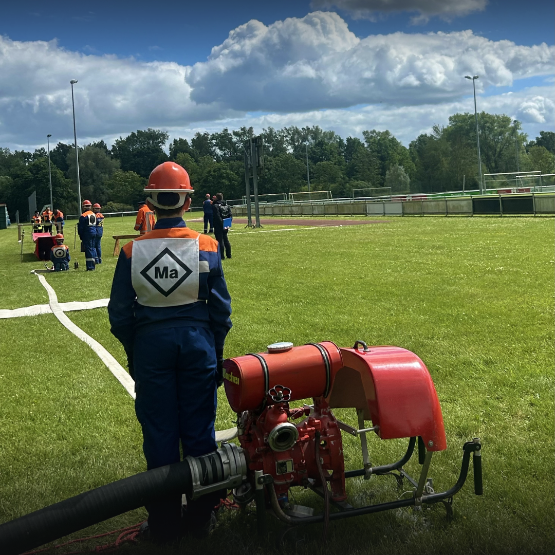 Jugendfeuerwehrmitglied steht neben Pumpe