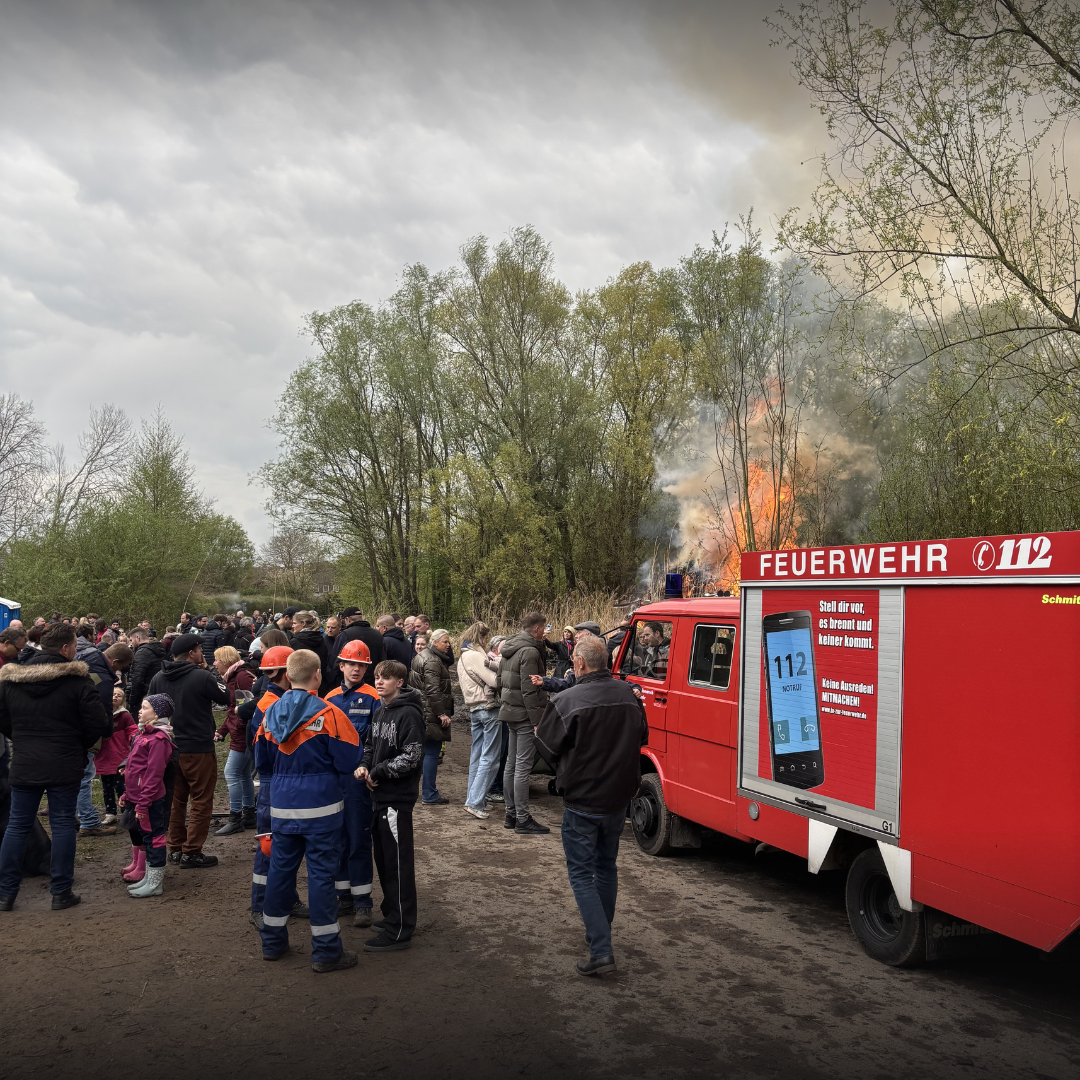 Viele Menschen, ein Feuerwehrfahrzeug und Feuer