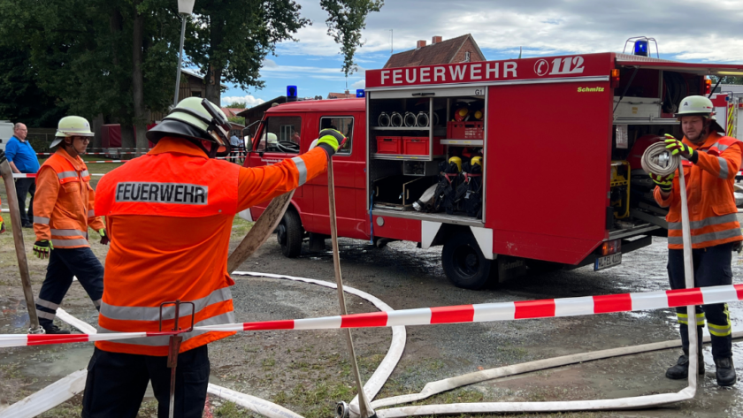 Feuerwehrleute und ein Feuerwehrfahrzeug hinter einer Absperrung