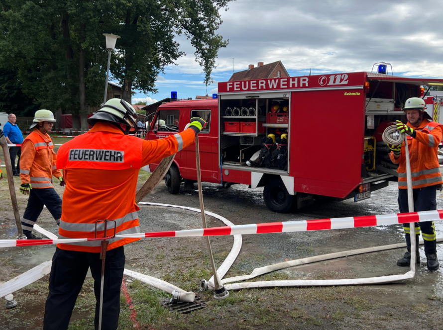 Feuerwehrleute und ein Feuerwehrfahrzeug hinter einer Absperrung